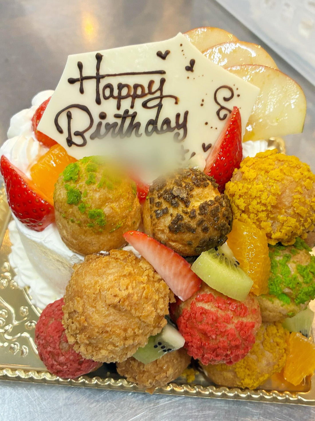 Happy Birthdayのプレートとカラフルなプチシュー、フルーツをのせたお誕生日ケーキ