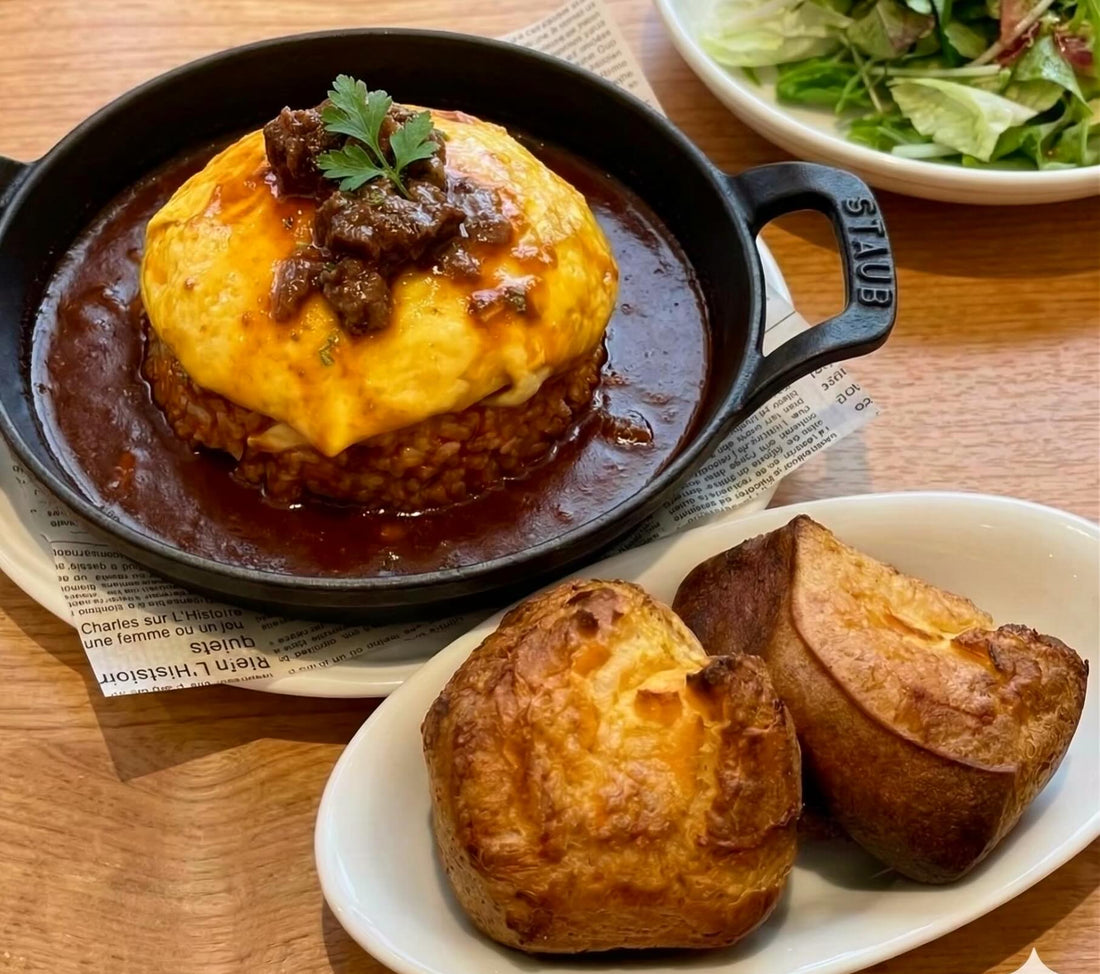 黒い鍋のオムライスと焼きたてのパン、サラダが並ぶ2つ3つのランチ