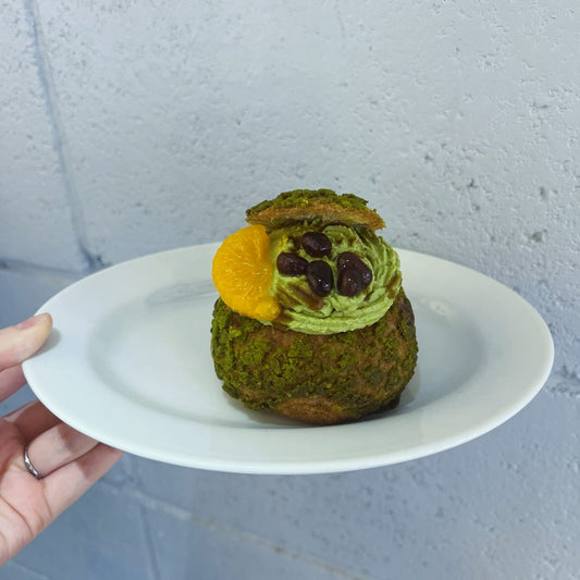 抹茶クリームと小豆、みかんをのせた抹茶のパフェシューを白い皿に盛った写真