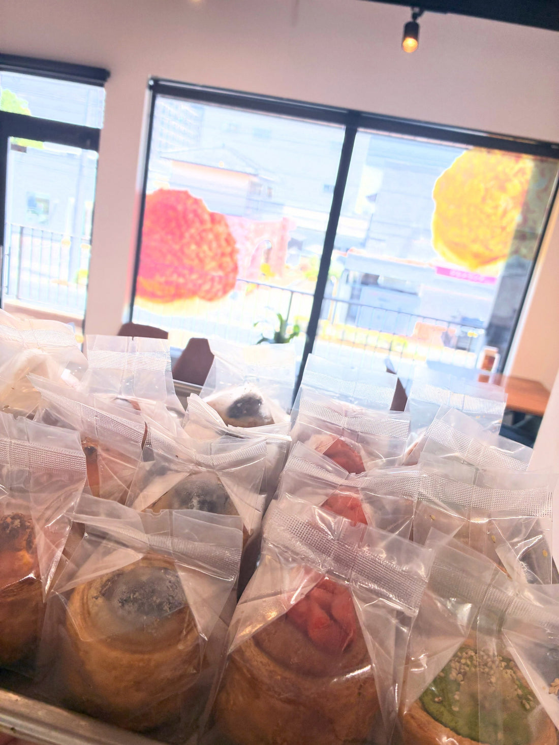 窓際の店内に、1個ずつ袋に入ったいちごや緑のクリームのパイが並んでいる様子