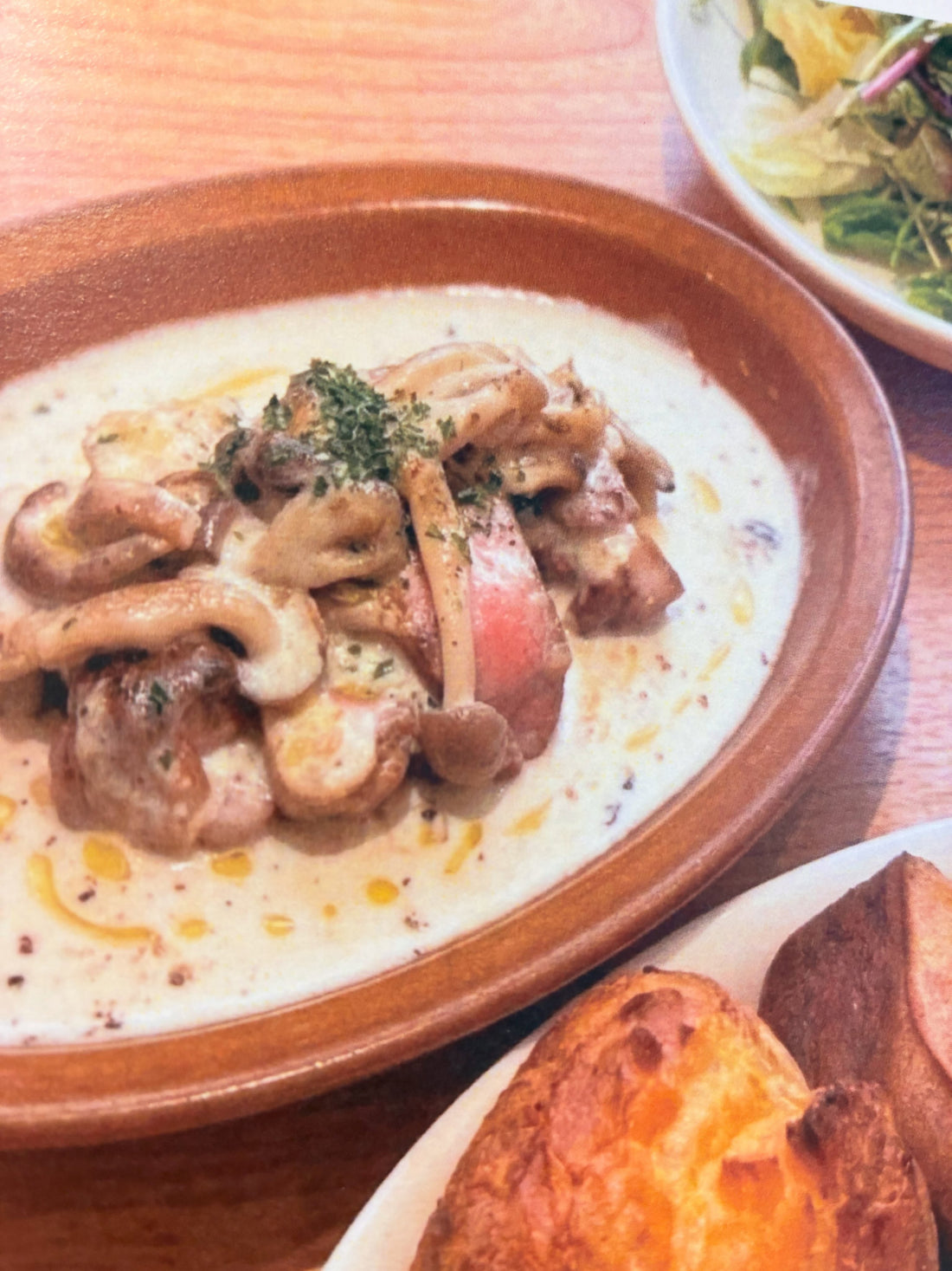 茶色の器に入った豚肉のグリルのきのこクリームソースと、手前のポップオーバー