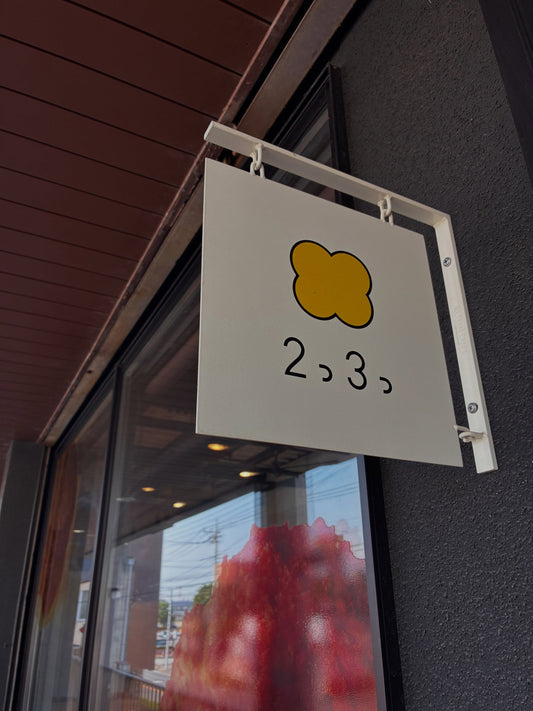 栃木県足利市のお店2つ3つの、黄色いマークと店名が入った白い吊り下げ看板