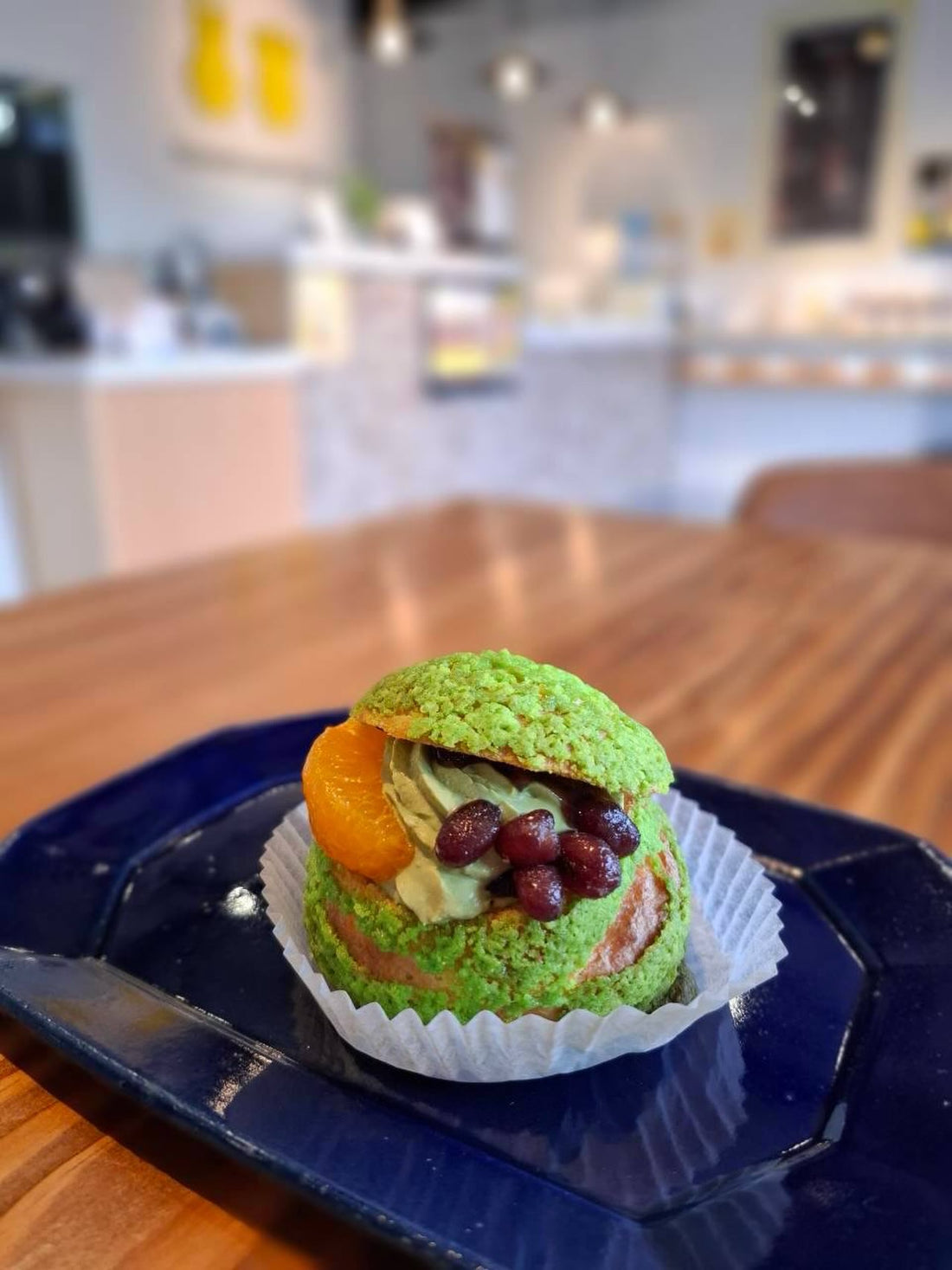 青いお皿にのった、緑のクランブル生地に小豆とみかんを添えた期間限定パフェシュー