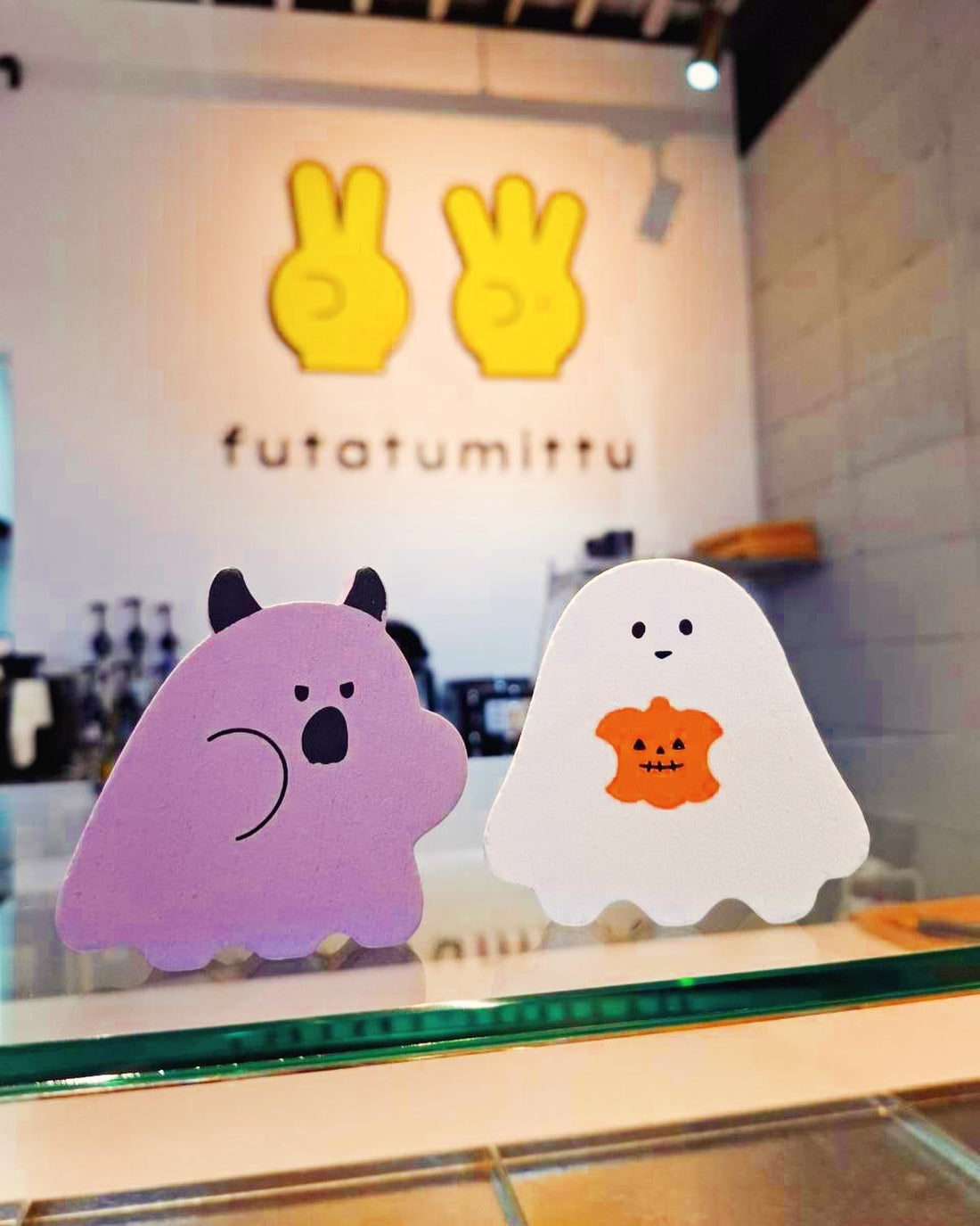 ショーケースに並ぶ紫のキャラクターとかぼちゃ柄の白いおばけの飾り