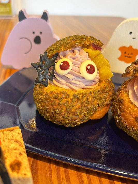 紺色のお皿にのった、紫芋クリームとさつまいもの目玉つきハロウィンシュークリーム