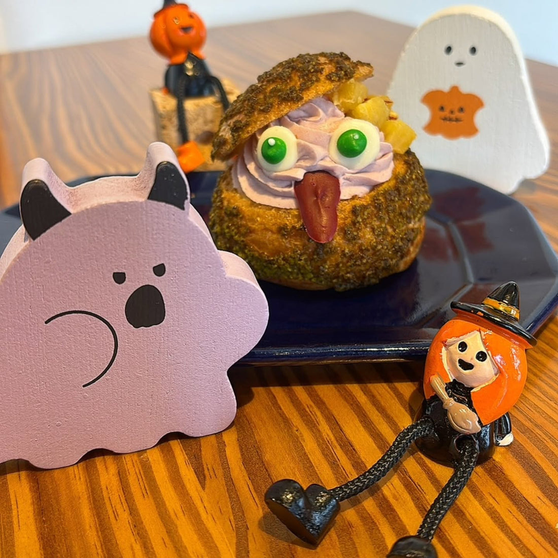 紺色のお皿にのった、紫のクリームと緑の目玉のおばけ顔ハロウィンパフェシュー