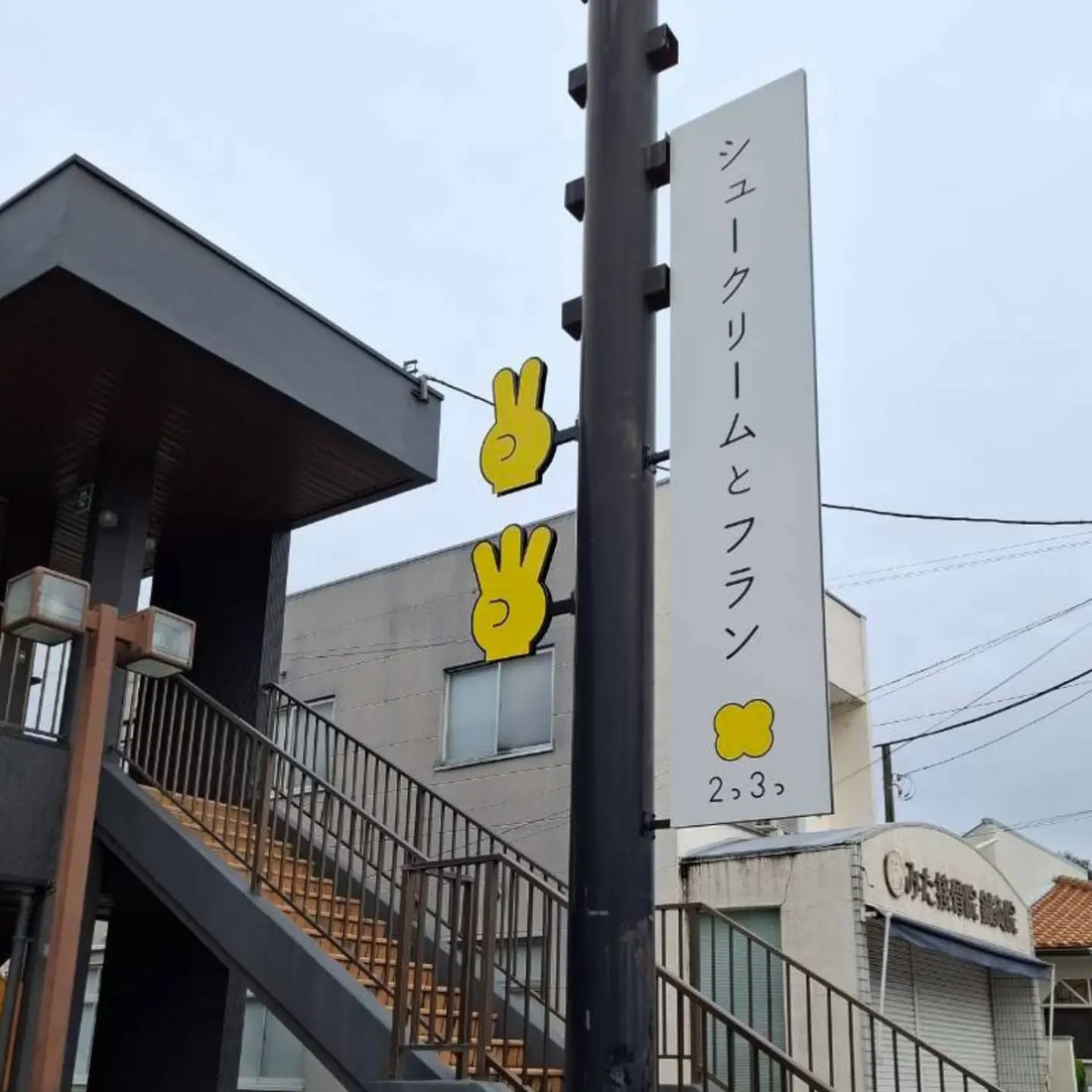シュークリームとフラン 2つ3つの白い縦長看板と、黄色い手の形の看板